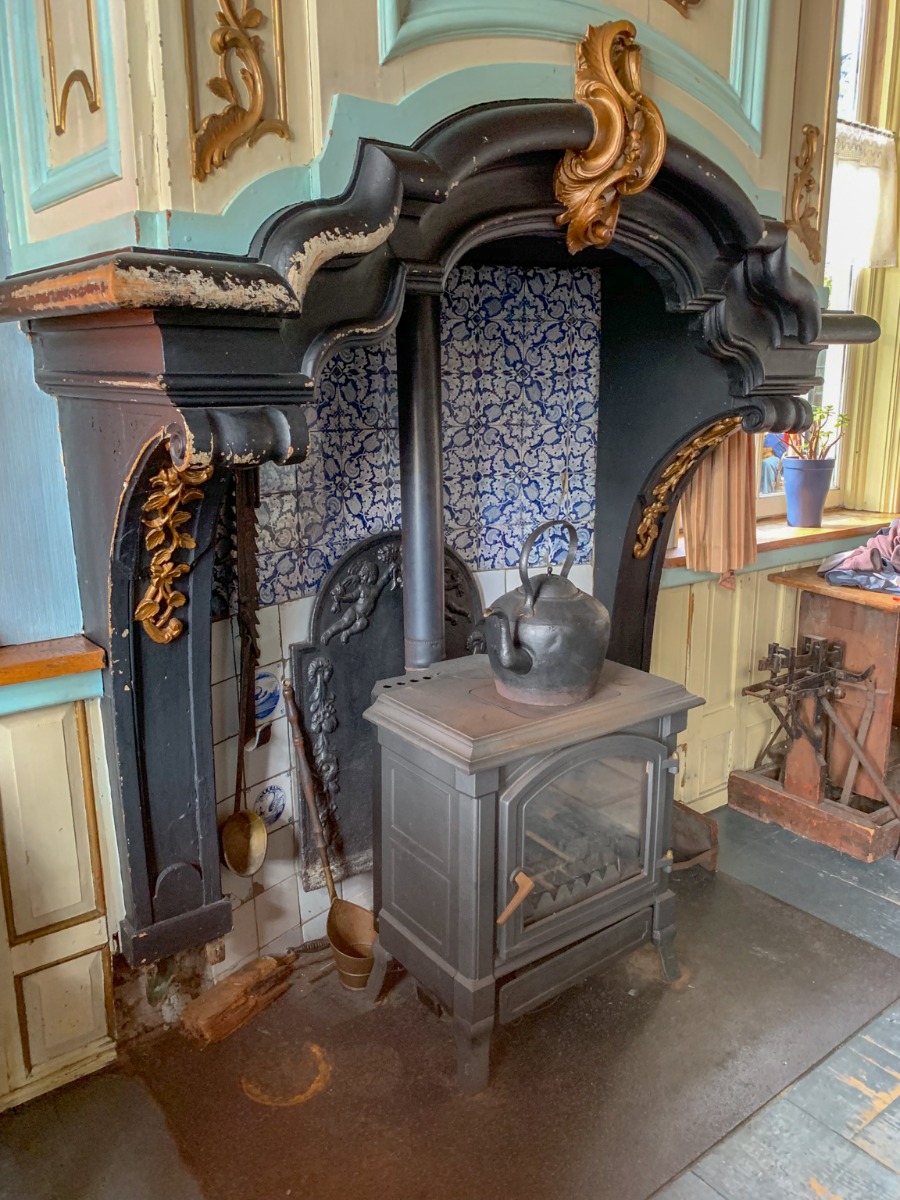 Antica piastra per camino olandese posta dietro una stufa in un antico caminetto olandese
